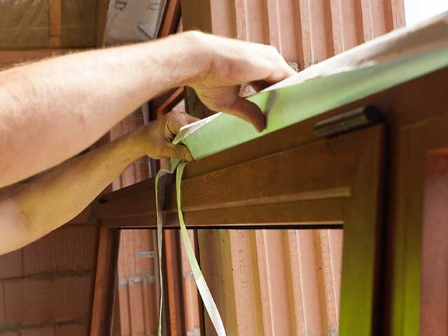 worker applying window frame sealing tape