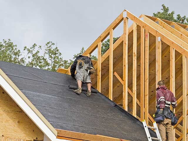 workers installing a roof on a new home build