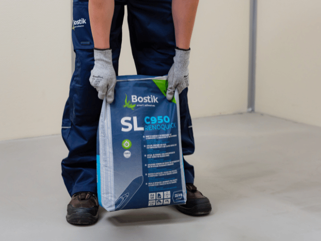 Pytel samonivelační a opravné hmoty Bostik SL C950 Renoquick o hmotnosti 25 kg. Produkt je připraven k použití při renovaci a opravách podlah a schodů.