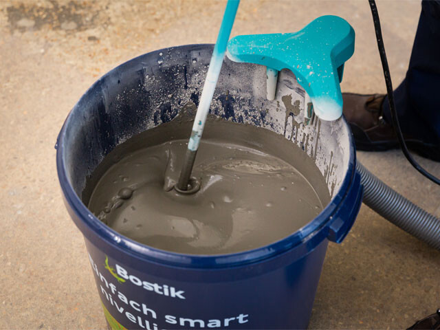 A blue bucket in which self-levelling compound is being mixed