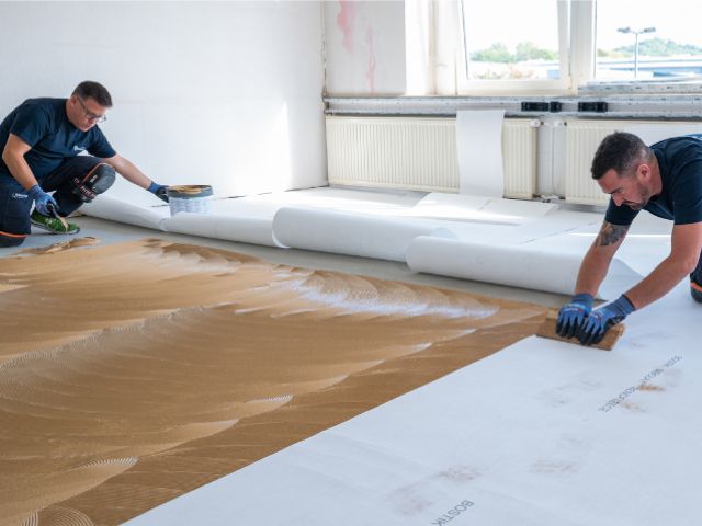 Installing Bostik decoupling underlay over adhesive