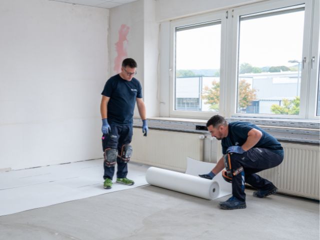 Rolling out Bostik decoupling underlay on a floor
