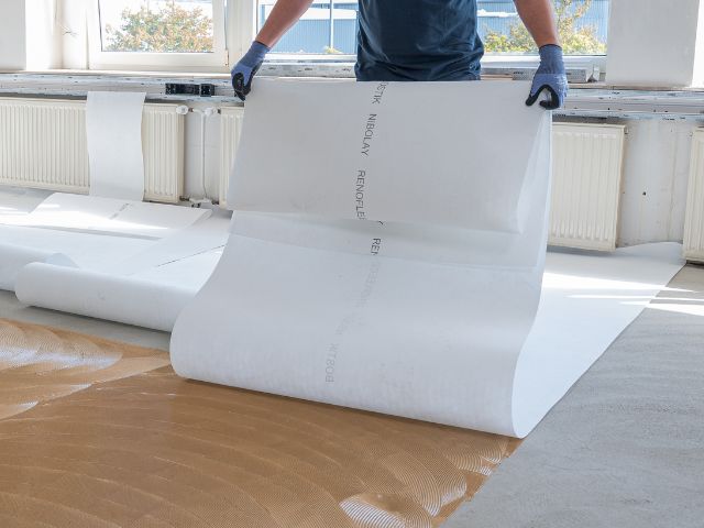 Laying Bostik decoupling underlay over adhesive