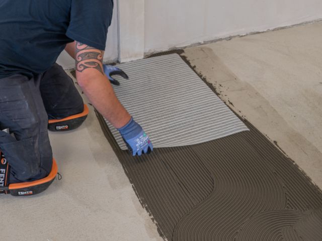 Placing bridging mesh onto floor adhesive