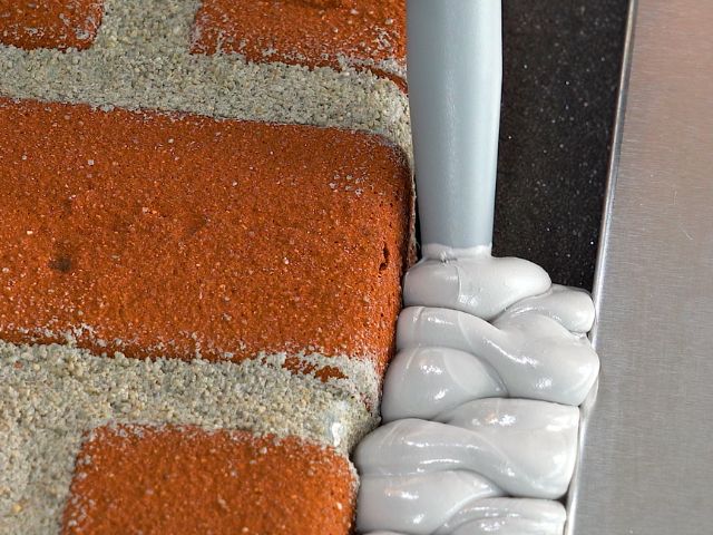 Close-up of Bostik chemical-resistant sealant applied around a metal fixture and brickwork joint, creating a durable flexible seal.