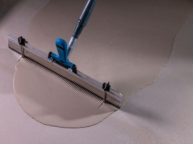 Spreading self-levelling compound with a gauge rake