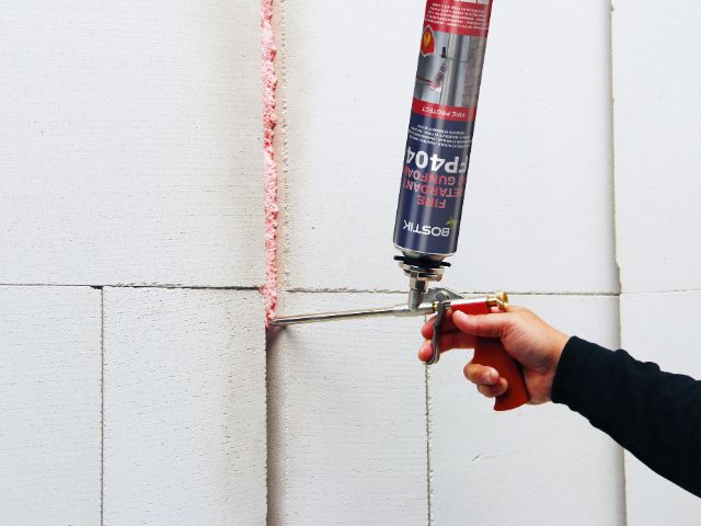 Bostik FP404 Fire Retardant PU Gun Foam being applied into a vertical joint between construction blocks to create a fire-resistant seal.