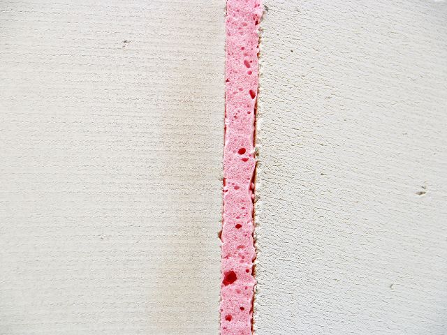 Close-up of Bostik FP404 Fire Retardant PU Gun Foam applied within a vertical construction joint, showing the expanded foam creating a fire-resistant seal between building elements.