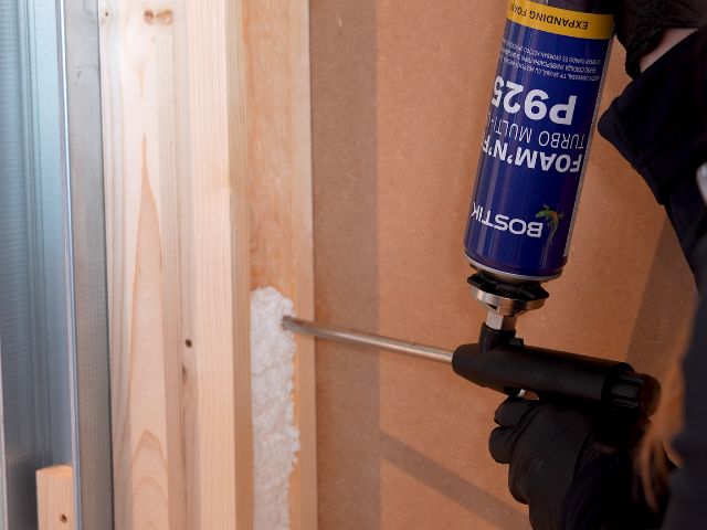 Bostik Foam'N'Fill Turbo Multi-Use P925 expanding foam being applied into a timber stud wall cavity with a foam gun, helping to improve sound insulation and reduce airborne noise transmission.
