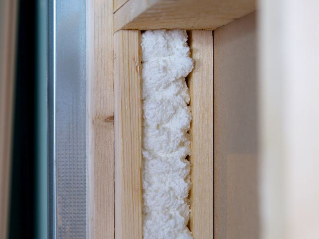 Close-up of cured Bostik expanding foam filling a cavity between timber studs, creating an insulated seal to help reduce sound transfer through wall constructions.