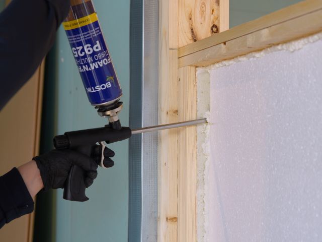 Bostik Foam'N'Fill Turbo Multi-Use P925 expanding foam being applied around the edge of a rigid insulation board within a timber frame wall, helping to seal gaps and improve acoustic performance.