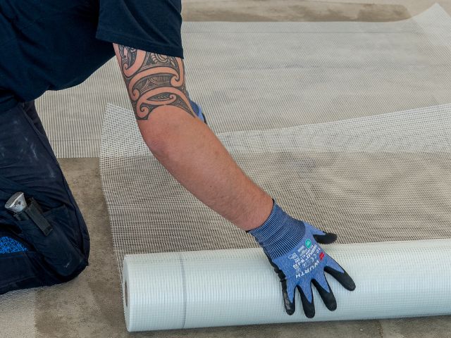 Rolling out reinforcing mesh on a concrete floor