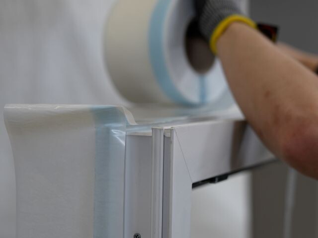 Bostik window insulation tape being applied along a window frame to create an airtight seal during installation.