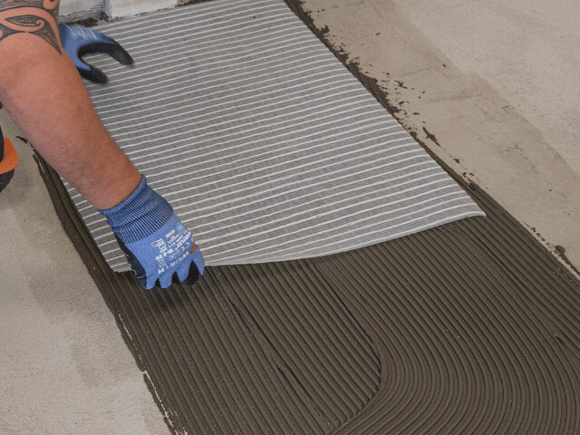 man placing underlay on treated floor surface