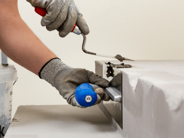 Bostik repair mortar being applied with a trowel to rebuild and smooth a damaged concrete edge.