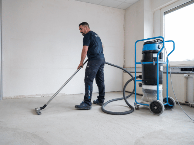 Concrete subfloor being cleaned with a professional vacuum system to remove dust before applying Bostik flooring solutions.