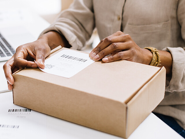 Courier adhering a packaging label to a cardboard box