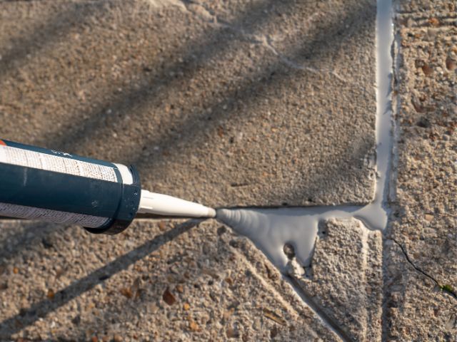 Duză de aplicare introduce etanșant Bostik într-o fisură a unei suprafețe din beton, asigurând umplerea uniformă și etanșarea de lungă durată a rostului.
