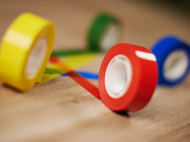 red, yellow, blue and green rolls of tape rolled out on a table