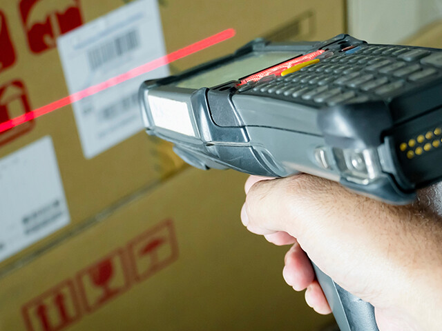 courier scanning a shipping label on a carboard box