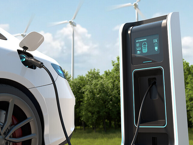 white electric car sitting in a parking spot, plugged in to an electric car charging station