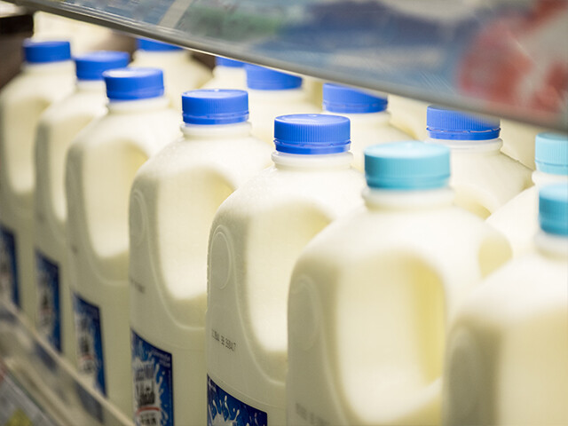 plastic milk jugs with wash-off labels sitting in a cooler in a grocery store