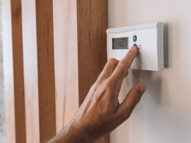 Hand stelt temperatuur in op een thermostaat