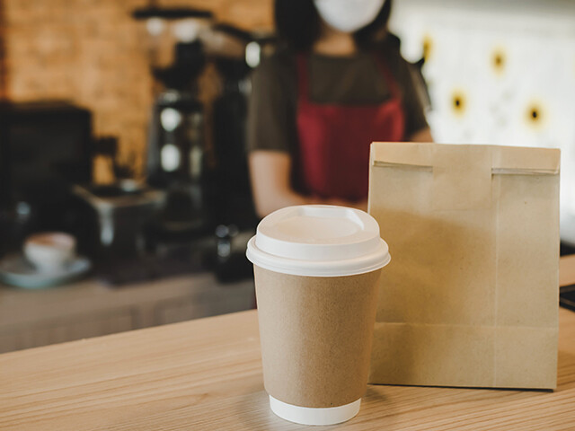 to go cup and paper bag sitting on a counter in a coffee shop